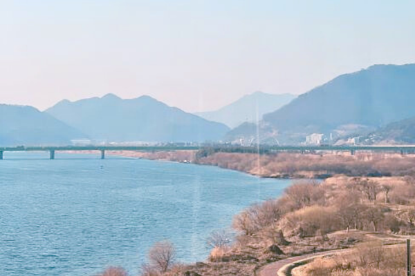 韓国・ヤンサンを流れる洛東江と遠くに続く山並み。澄んだ青空の下で自然と遊歩道が調和する癒しの景観