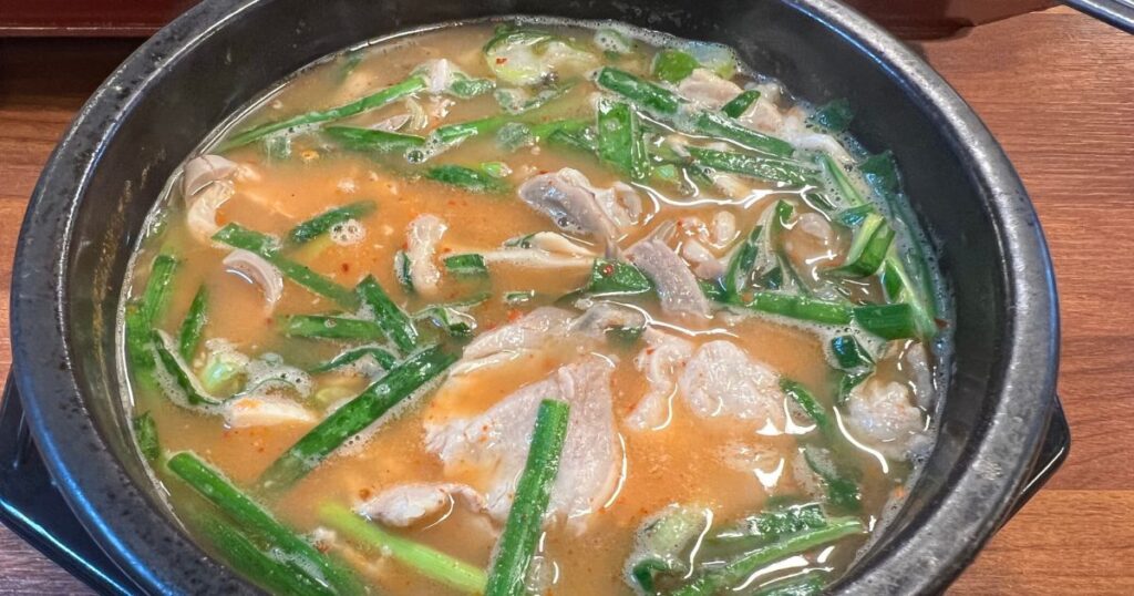 釜山の食堂で供される、湯気の立つトゥッペギのデジクッパ。ニラと豚肉がたっぷり入った素朴な一杯。
