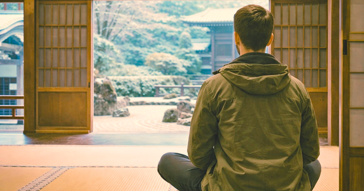 冬の円覚寺で、枯山水の庭園を前に座禅を組むカジュアルな服装の外国人男性の後ろ姿